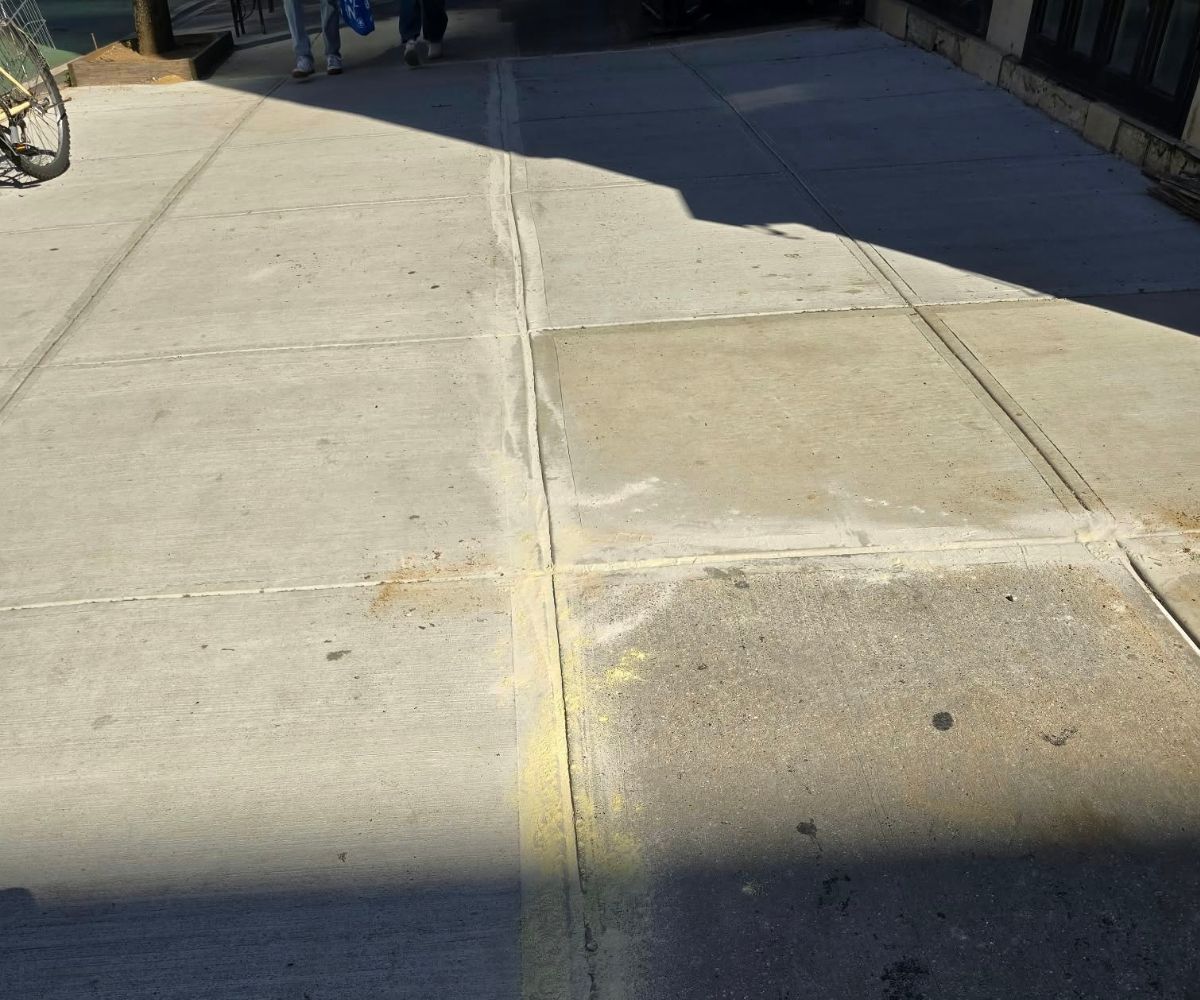 Newly repaired concrete sidewalk with level flags and clean joints outside a townhouse on East 95th Street in Carnegie Hill, Manhattan.