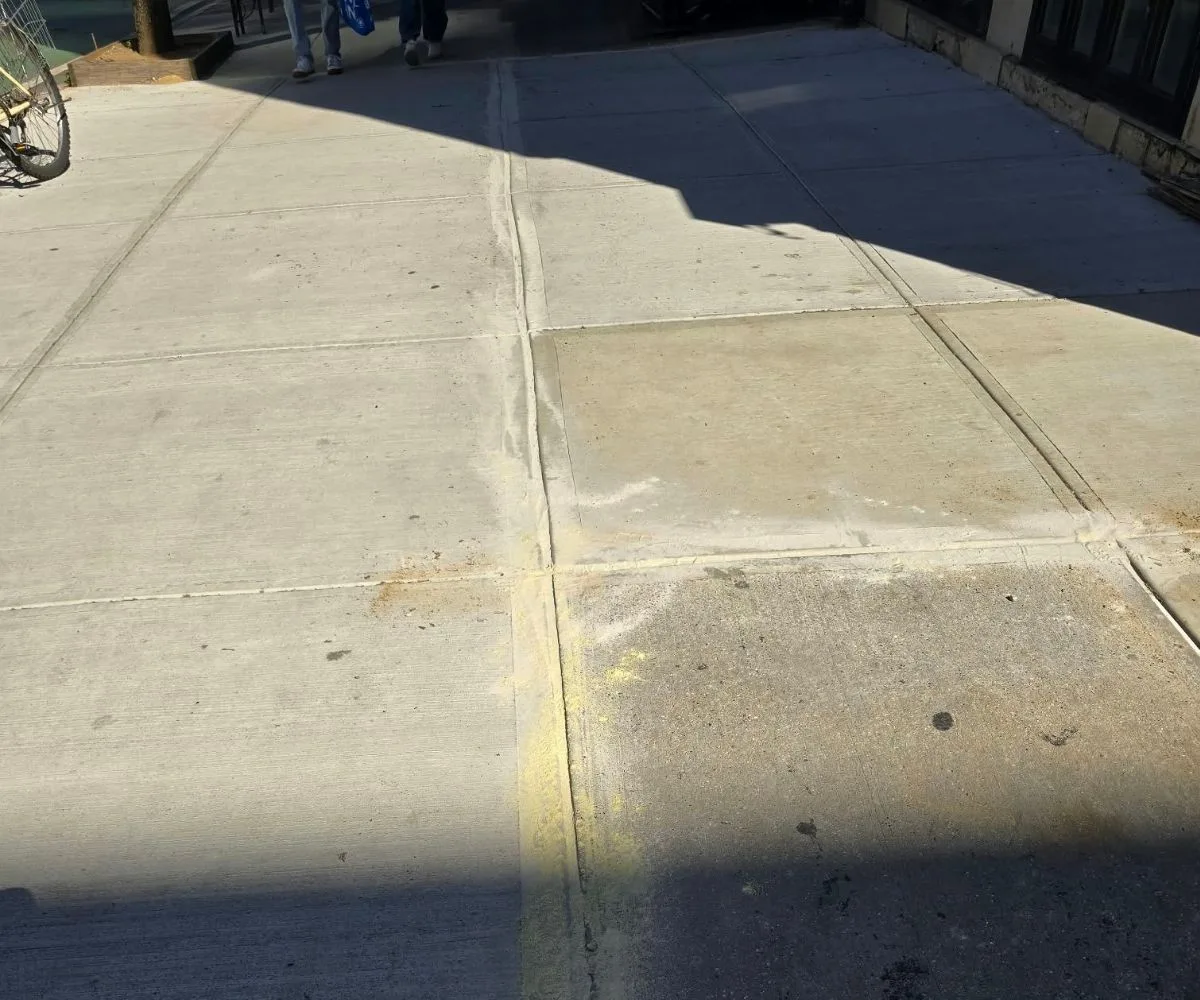 Newly repaired concrete sidewalk with level flags and clean joints outside a townhouse on East 95th Street in Carnegie Hill, Manhattan.
